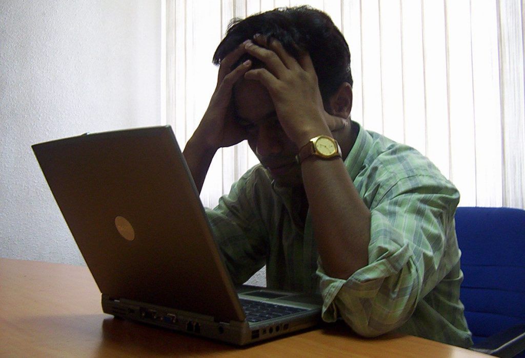 Man looking at laptop and stressed