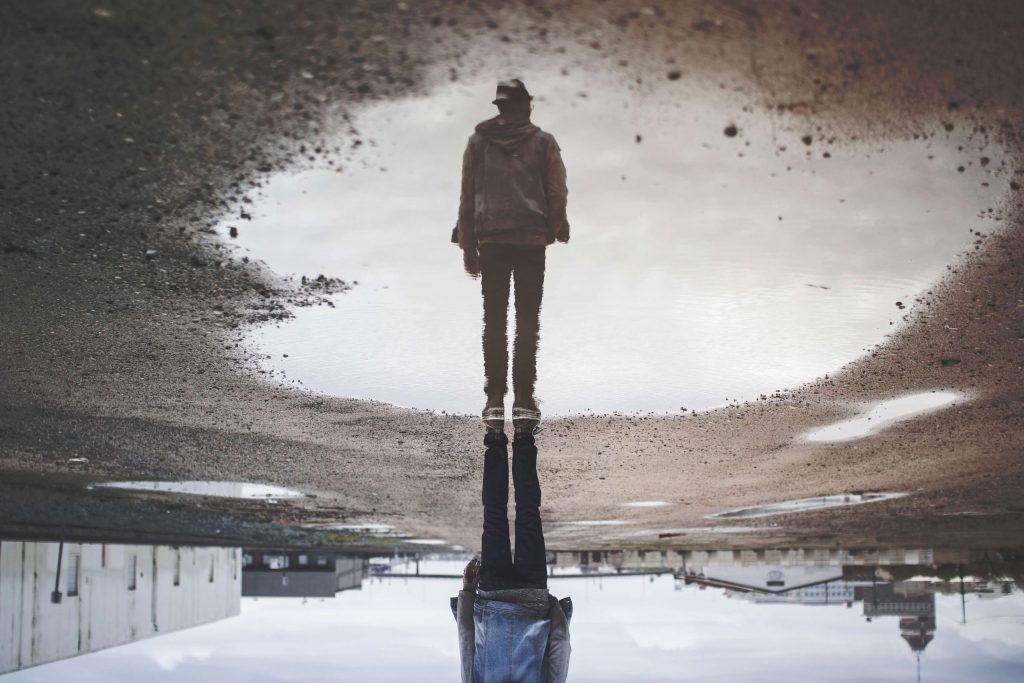 man reflected in a puddle